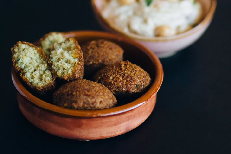BookNoFees: Örnek fotoğraf: Kâsede biri kesilmiş falafel topları ve arkada humus