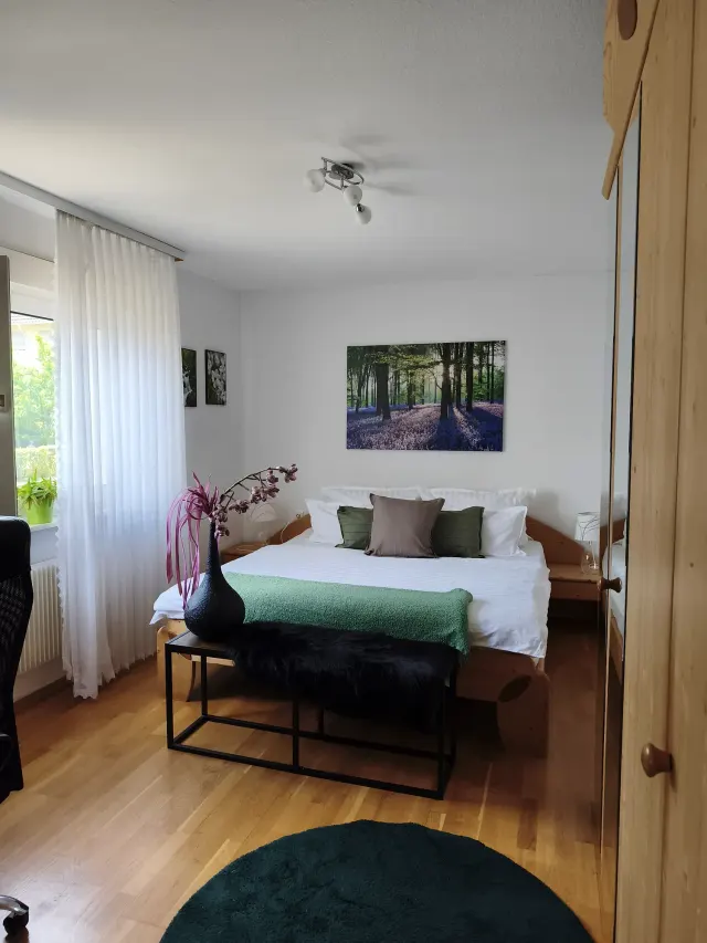 BookNoFees tatil evi: Bensheim, Hessen, Almanya – Çift kişilik yatak, orman temalı sanat eseri ve ahşap gardırop bulunan yatak odası
