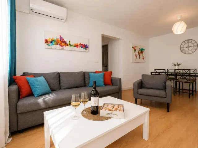 BookNoFees tatil evi: Jerez De La Frontera – Jerez de la Frontera’daki Buleria’da, bir kanepe ve üzerinde şarap kadehleri bulunan bir masa bulunan bir oturma odası