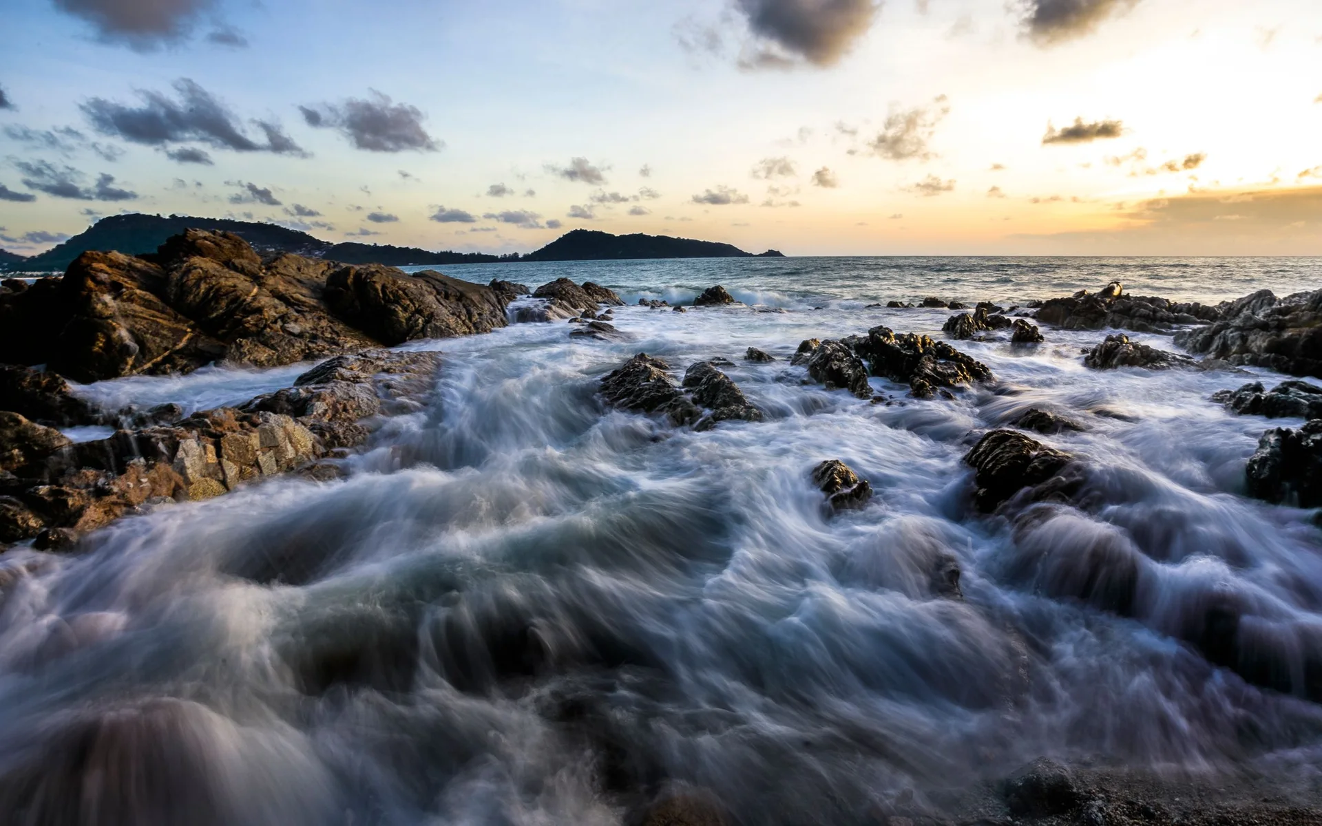 Gün batımında Phuket'in kayalık sahilindeki dalgalar