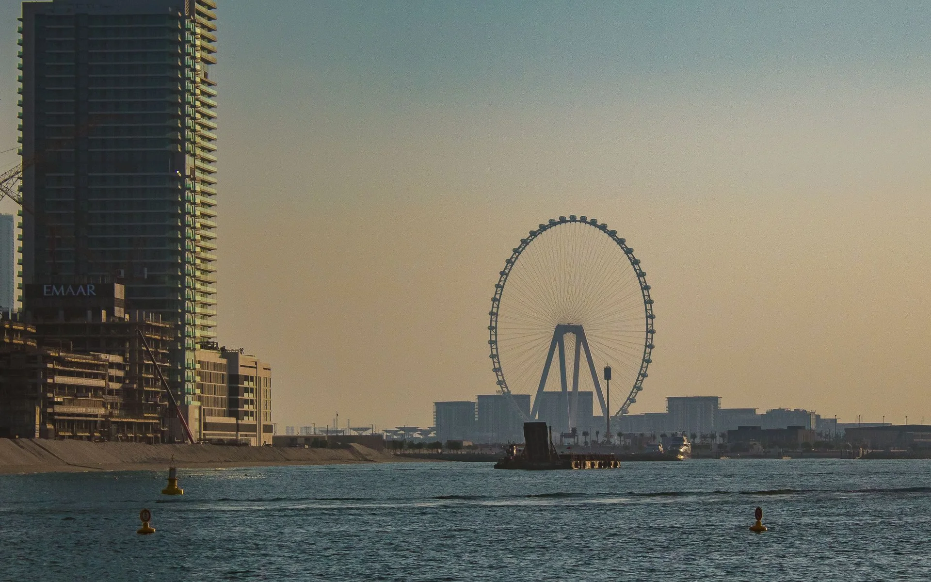 Gün batımında dev dönme dolabın bulunduğu Dubai silüeti