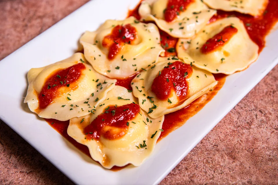 Example photo: Ravioli topped with tomato sauce and herbs on a white plate