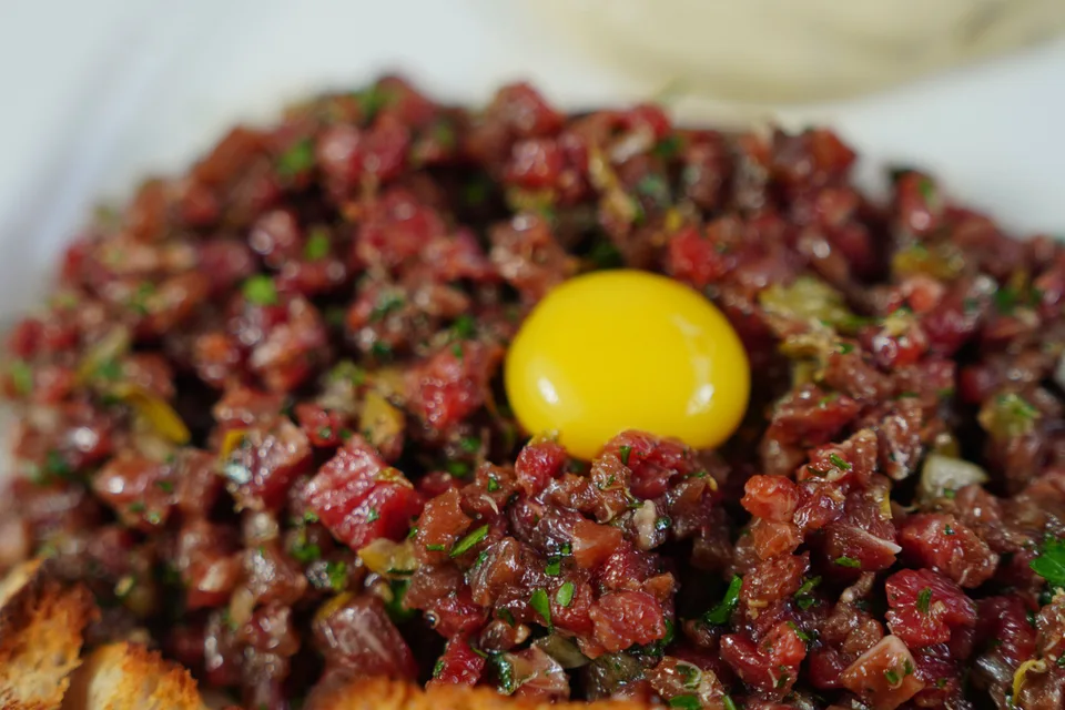 Example photo: Steak tartare topped with egg yolk and served with toasted bread